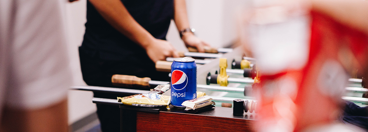 Pepsi can with students playing pool in the background
